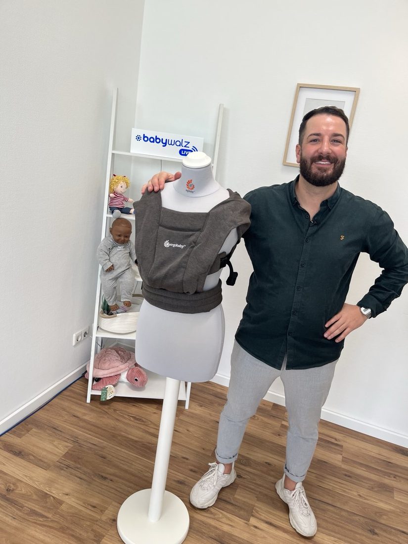 Ozan Bilgin mit einer Ergobaby-Babytrage bei einem Livestream von baby-walz